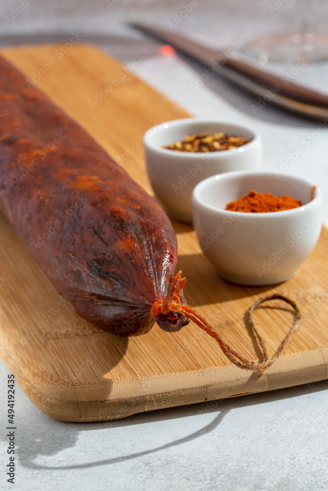 Fototapeta premium Kulen on wooden cutting board. Meat sausage made of minced pork with red paprika, traditionally produced in Croatia and Serbia.