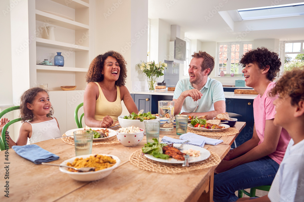 Family Sitting Around Table At Home Eating Meal Together Family Sitting Around Table At Home Eating Meal Together