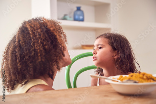 Mother With Daughter Who Is Fussy Eater Sitting Around Table At Home For Family Meal  photo