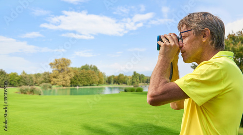 Принти на полотні The golfer accurately measures the distance to the flag in a golf course with the laser rangefinder