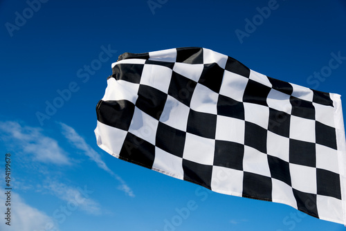 Checkered race flag waving on sky