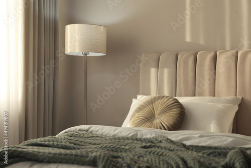 Stylish floor lamp near bed in room. Interior element