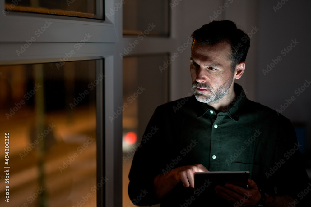 Adult caucasian man using digital tablet at the office and looking away Adult caucasian man using digital tablet at the office and looking away