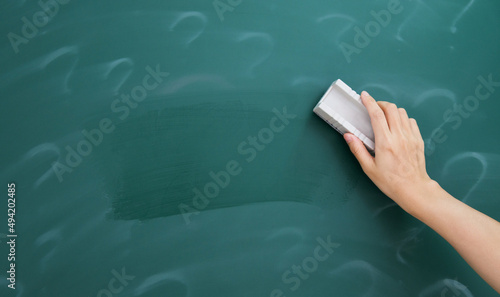 Hand erasing question mark on chalkboard