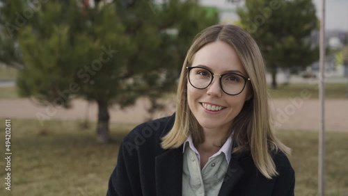 Portrait of smiling young girl in glasses sitting outdoors in the park Video HD