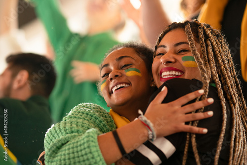 Brazilian young sisters football fans celebrating their team's victory at stadium. photo