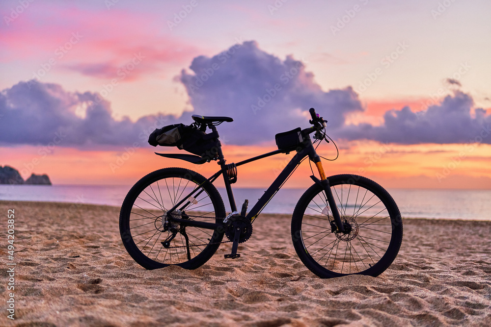 Bicycle on sandy sea coast against backdrop of pink idyllic sunset. Active vacation time Bicycle on sandy sea coast against backdrop of pink idyllic sunset. Active vacation time