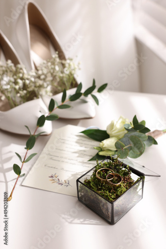 Bild auf Leinwand Beautiful wedding rings in glass box, boutonniere, bride's shoes and invitation