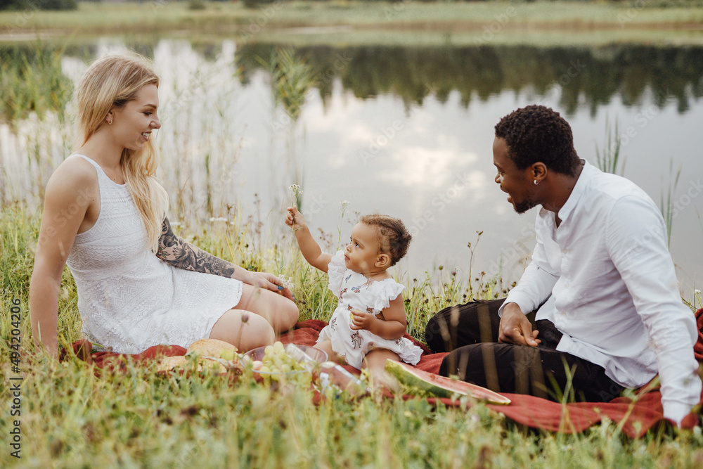 Multiracial family of couple with their child outdoors Photos | Adobe Stock