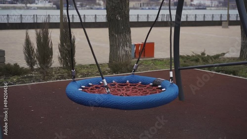 Empty baby swing swinging on the playground