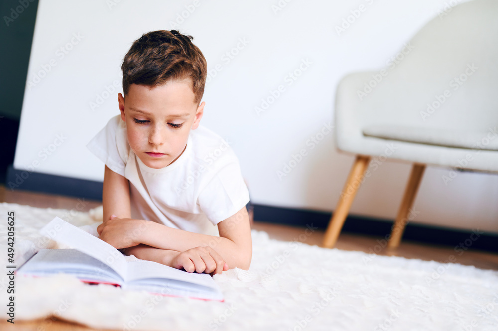 Education concept. Caucasian boy laying down on the floor and reading books at home Education concept. Caucasian boy laying down on the floor and reading books at home