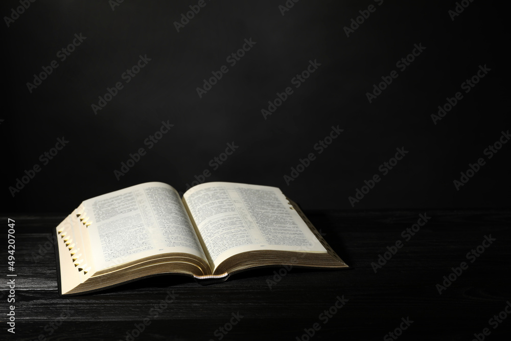 Open Bible on black wooden table, space for text. Christian religious book Open Bible on black wooden table, space for text. Christian religious book
