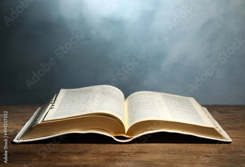 Valokuva Open Bible on wooden table against color background