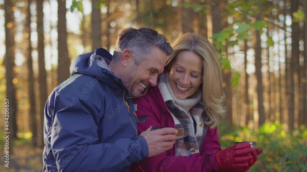 Loving mature couple stop for rest and hot drink on walk through fall or winter countryside - shot in slow motion Loving mature couple stop for rest and hot drink on walk through fall or winter countryside - shot in slow motion