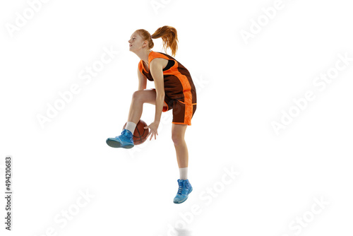 Portrait of young active girl, basketball player training, dribblig ball in a jump isolated over white studio background.