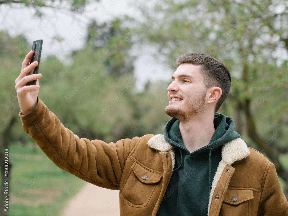 Hombre joven haciéndose un selfie en un parque Hombre joven haciéndose un selfie en un parque