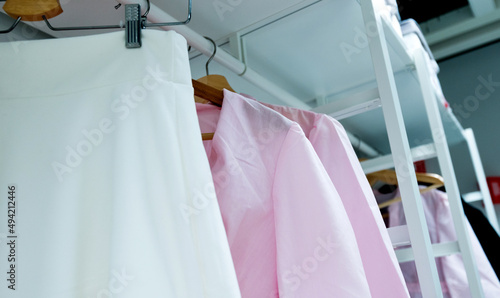 Row of cloth hangers with female pink shirts
