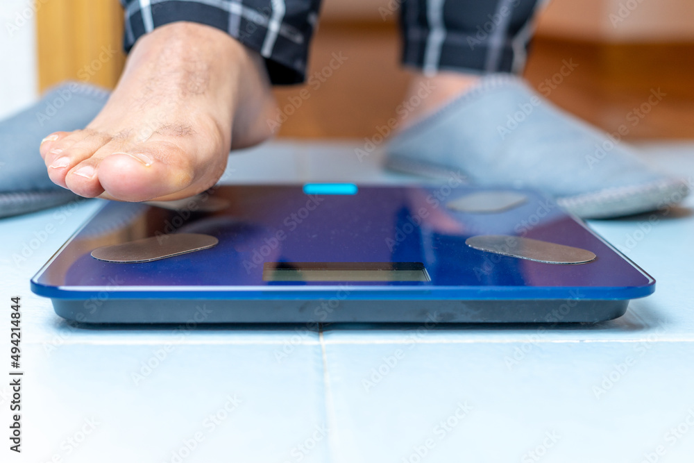 Close up of a mature man's foot as he is about to place it on an electronic weight scale. Weight control concept. High quality photo Close up of a mature man's foot as he is about to place it on an electronic weight scale. Weight control concept. High quality photo