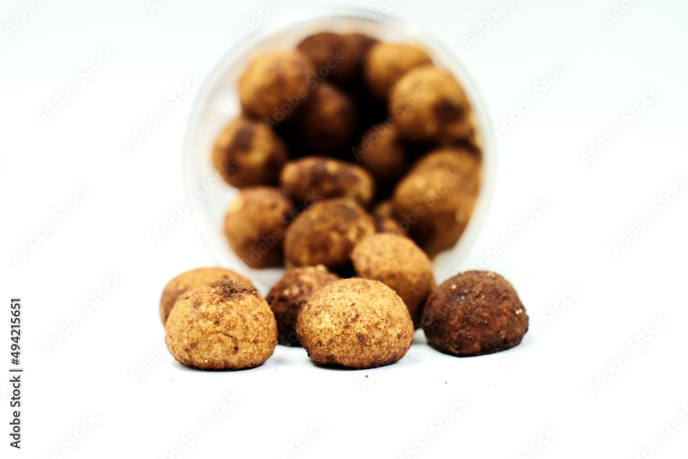 Tasty sweet chocolate truffles on a white table with a container on the background Tasty sweet chocolate truffles on a white table with a container on the background