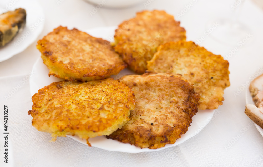 Potato pancakes with sour cream on white plate Potato pancakes with sour cream on white plate