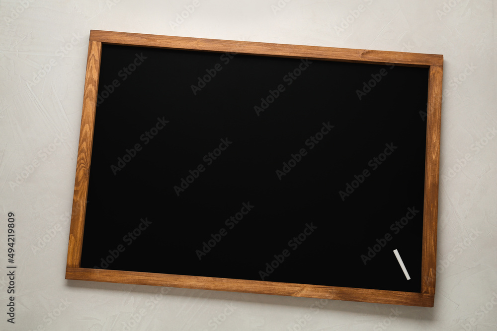 Clean blackboard with piece of chalk on light table, top view Clean blackboard with piece of chalk on light table, top view