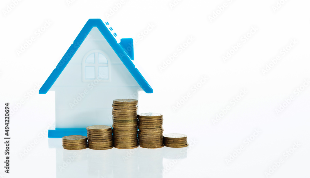 View Of coin stack with house model against white background View Of coin stack with house model against white background