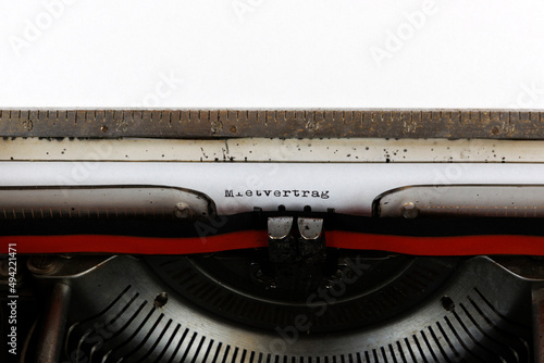 The German word Mietvertrag written in red on an old mechanical typewriter German Text: lease