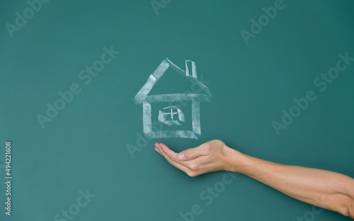 Hand protect a house on chalkboard