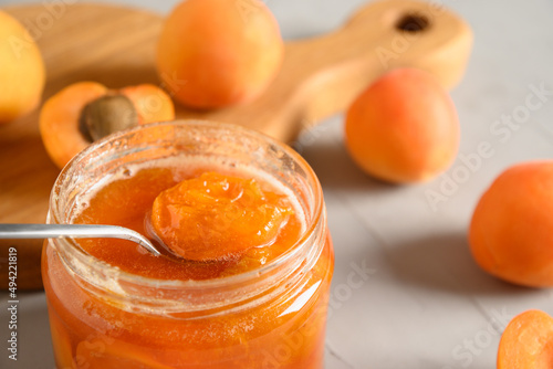 Apricot jam or confiture in open glass jar on white background. Summer harvest and canned food. Tasty dessert. Close up. photo