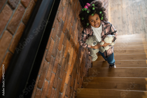 Top view of girl with toys standing on stairs