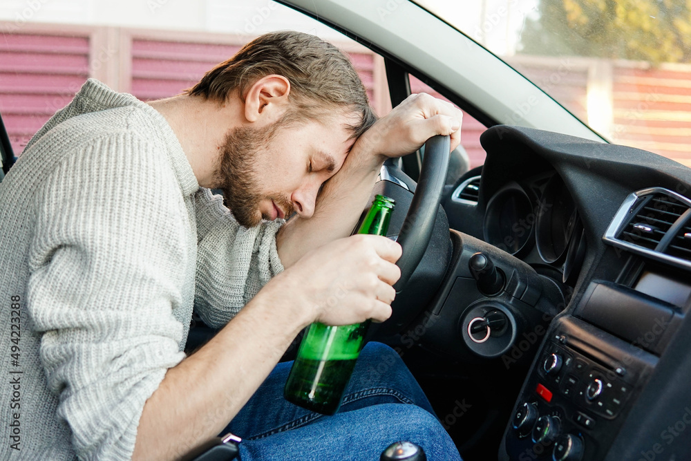 Young drunk man fall asleep behind the wheel of a car. Male car driver ...