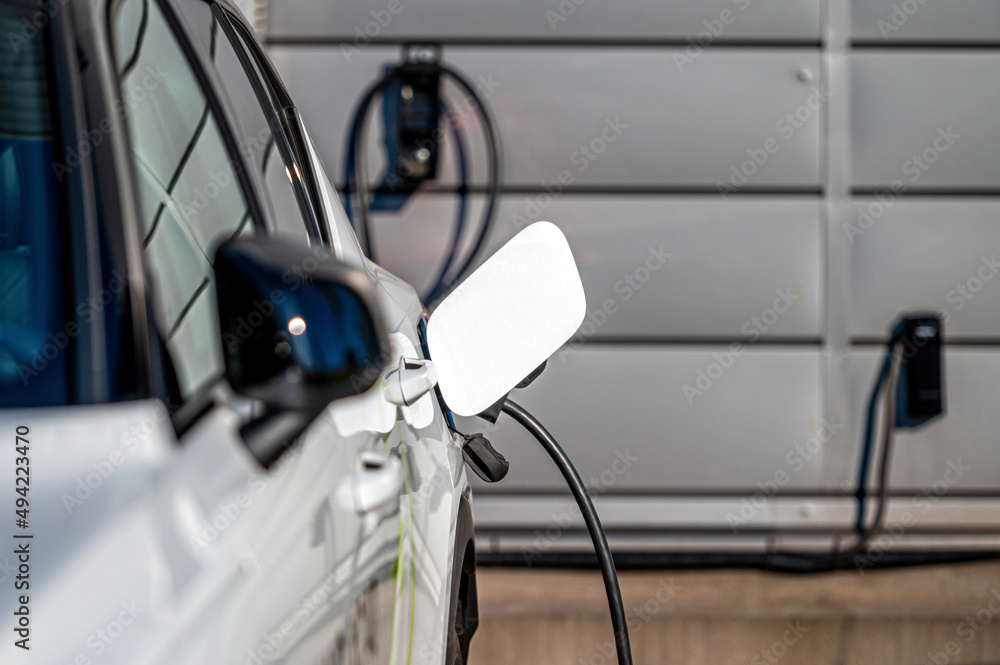 The electric car charger plugged in to the socket.The modern electric car charging the battery The electric car charger plugged in to the socket.The modern electric car charging the battery