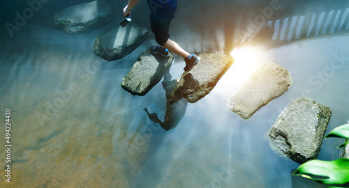 Man across stepping stones to cross a stream