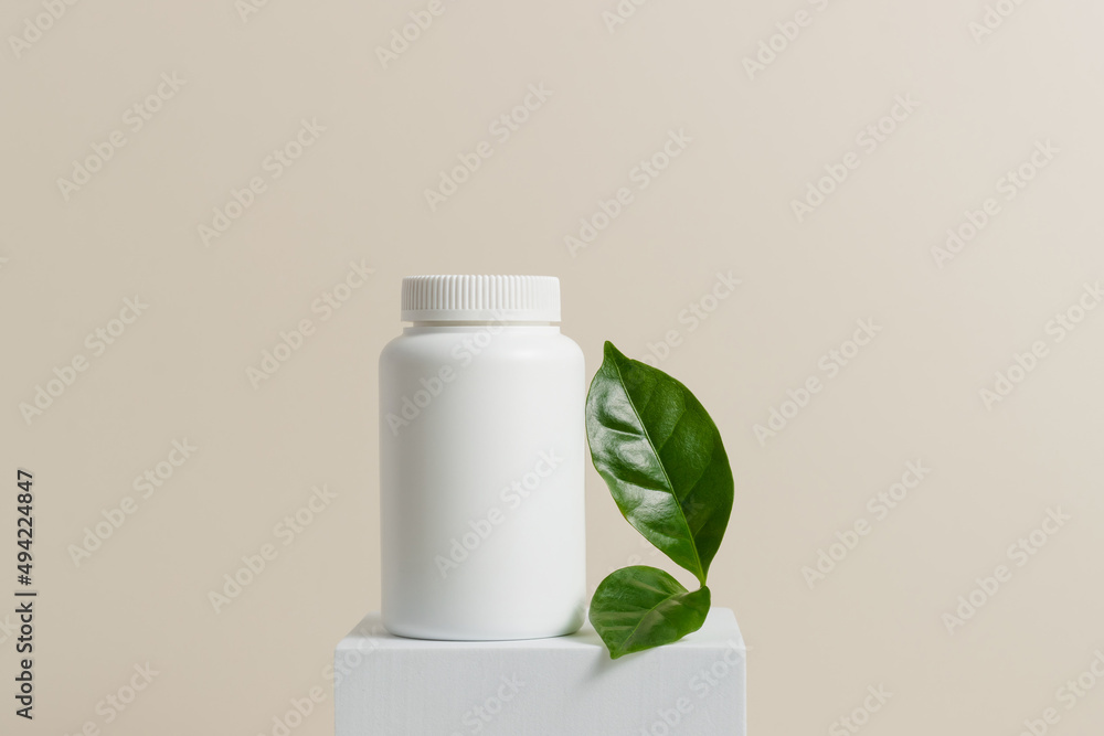 Mockup container for pills, capsules and vitamins on white stand with green leaf. White bottle with natural bio supplement, healthy lifestyle Mockup container for pills, capsules and vitamins on white stand with green leaf. White bottle with natural bio supplement, healthy lifestyle