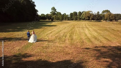 Wallpaper Mural Newlywed Couple In Suit And Wedding Gown Walking At The Field On A Sunny Day. Wedding Photoshoot. aerial Torontodigital.ca