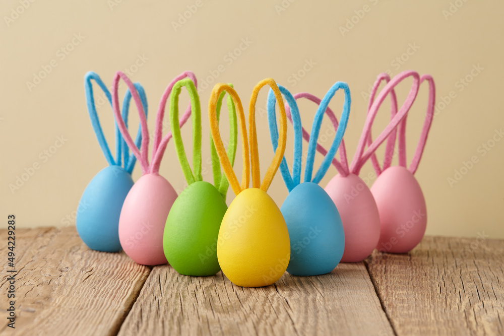 Colorful Easter eggs with bunny ears on beige background Colorful Easter eggs with bunny ears on beige background