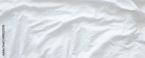 White wrinkled fabic texture rippled surface wide background,Close up unmade bed sheet in the bedroom after night sleep Soft focus photo