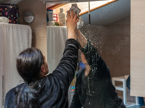 housewife cleans a mirror