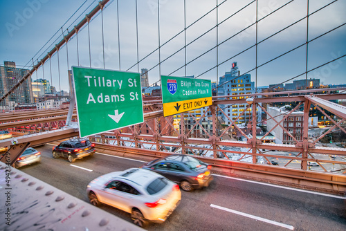 Cars speeding at sunset on Brooklyn Bridge at sunset, Manhattan. One of the most iconic bridges in the world, NY - USA.