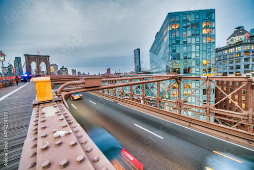 Cars speeding at sunset on Brooklyn Bridge at sunset, Manhattan. One of the most iconic bridges in the world, NY - USA.