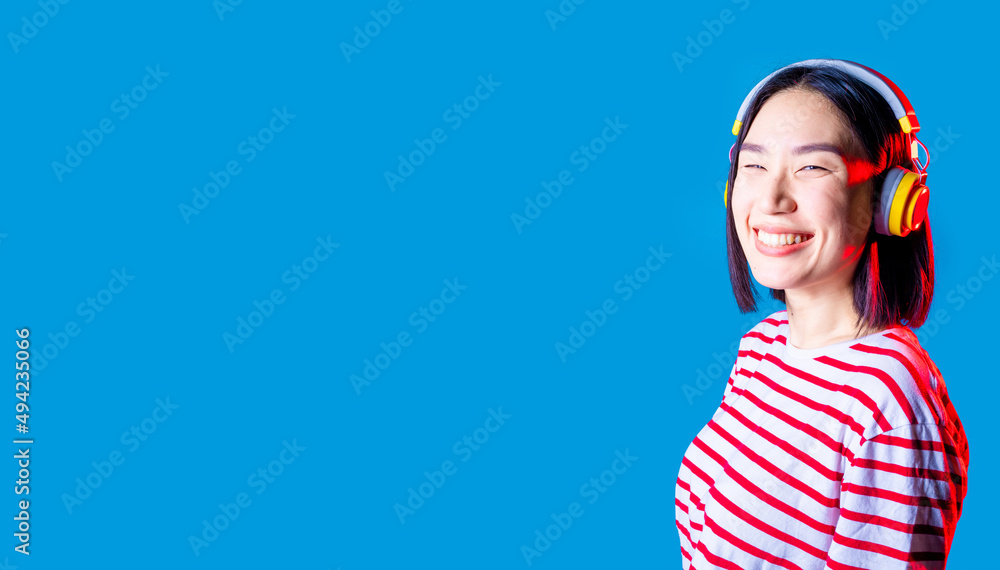 Fototapeta premium serene asiatic woman isolated on blue background listening music