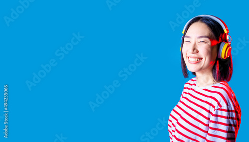 serene asiatic woman isolated on blue background listening music