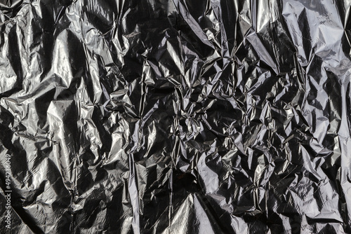 Black dark silver crumpled plastic material texture background
