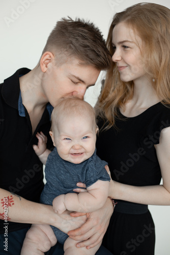 Vertical photo smiling calm family, woman, man and baby, kissing and spending time together. Father daughter. Bonding