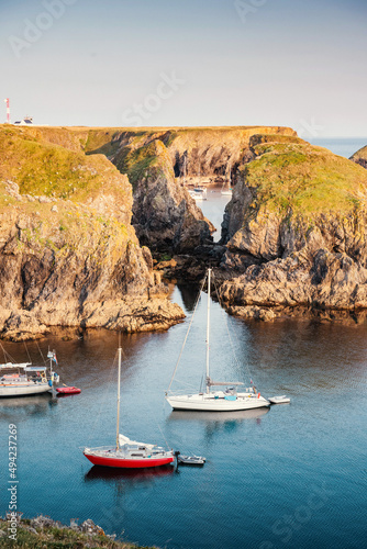 The quiet bays on the rocky coast of the island of Belle Ile en Mer provide a sheltered anchorage for many sailboats in the quiet sunset.