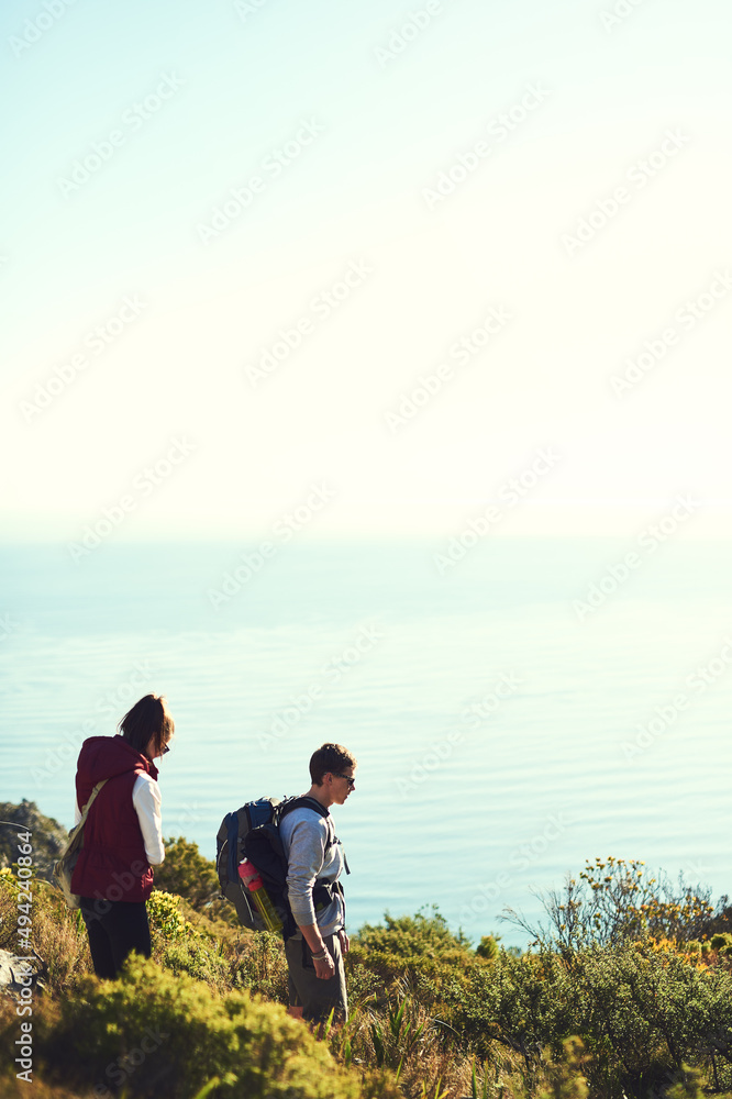 The mountains are calling. Shot of a young couple exploring the outdoors on a hiking trail.