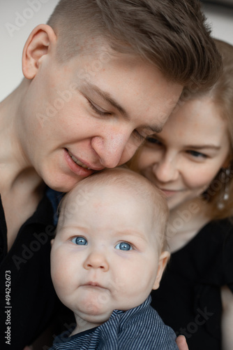 Vertical photo smiling calm family, woman, man and baby, kissing and spending time together. Father daughter. Close up