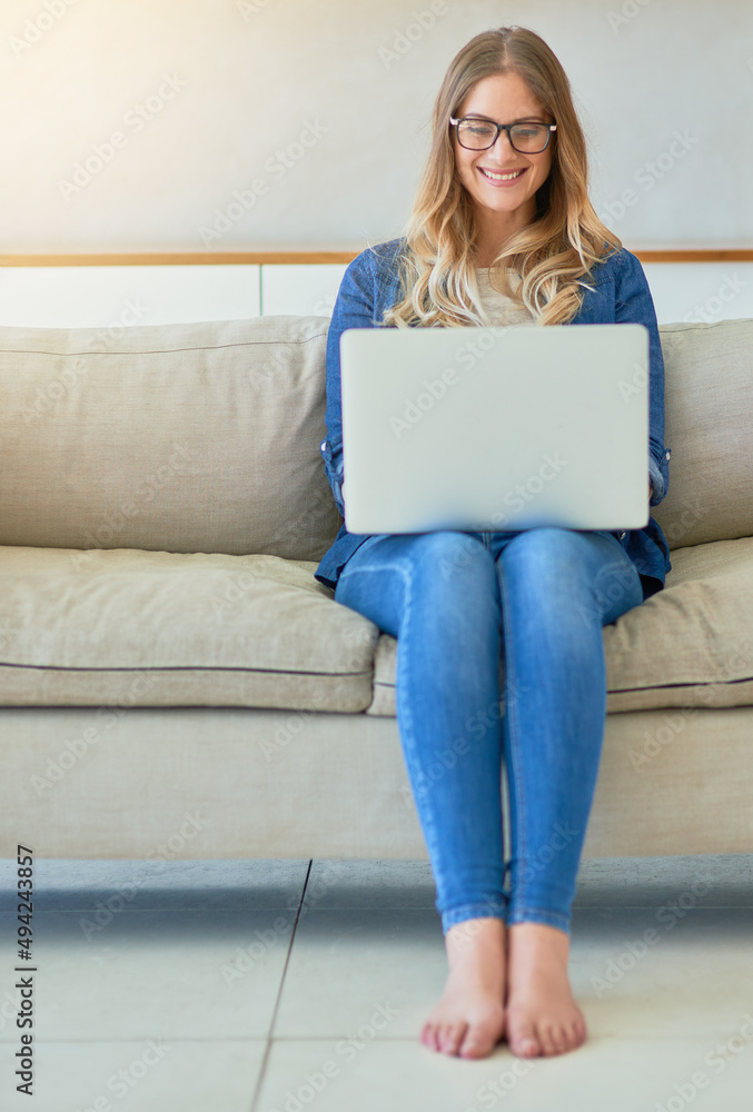 Getting her weekend dose on internet. Shot of an attractive young woman using her laptop while sitting on the sofa at home. Getting her weekend dose on internet. Shot of an attractive young woman using her laptop while sitting on the sofa at home.