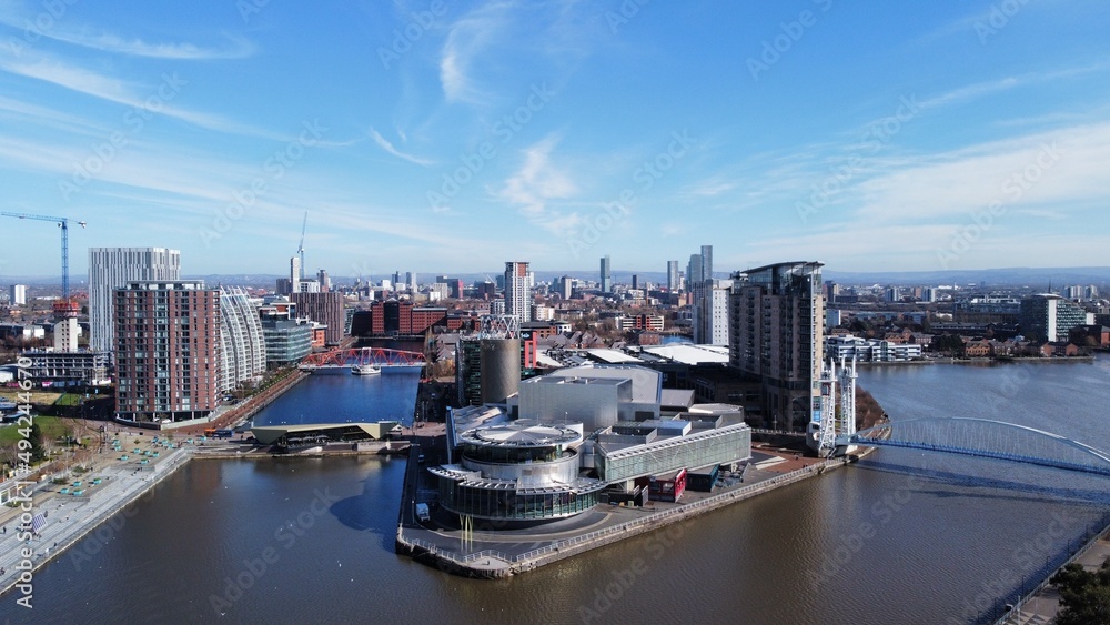 Drone image of Salford Quays with modern buildings and landmarks and views towards Manchester. 