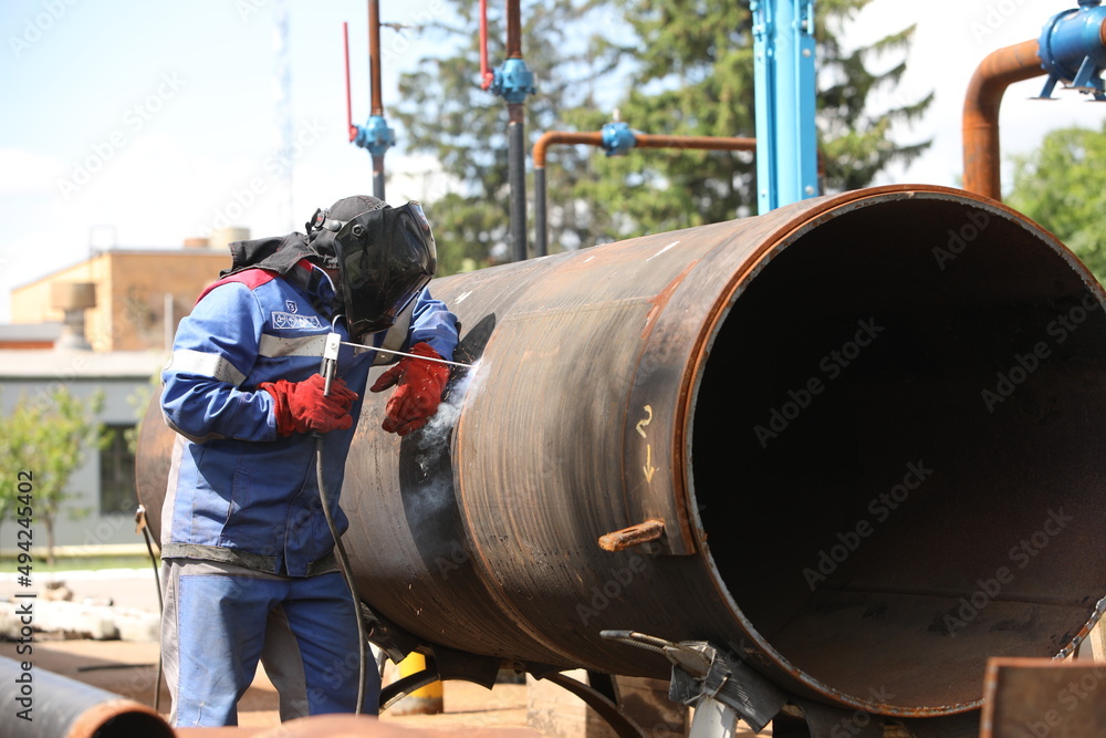 Male welder works. Welding joint of large diameter pipe. High pressure